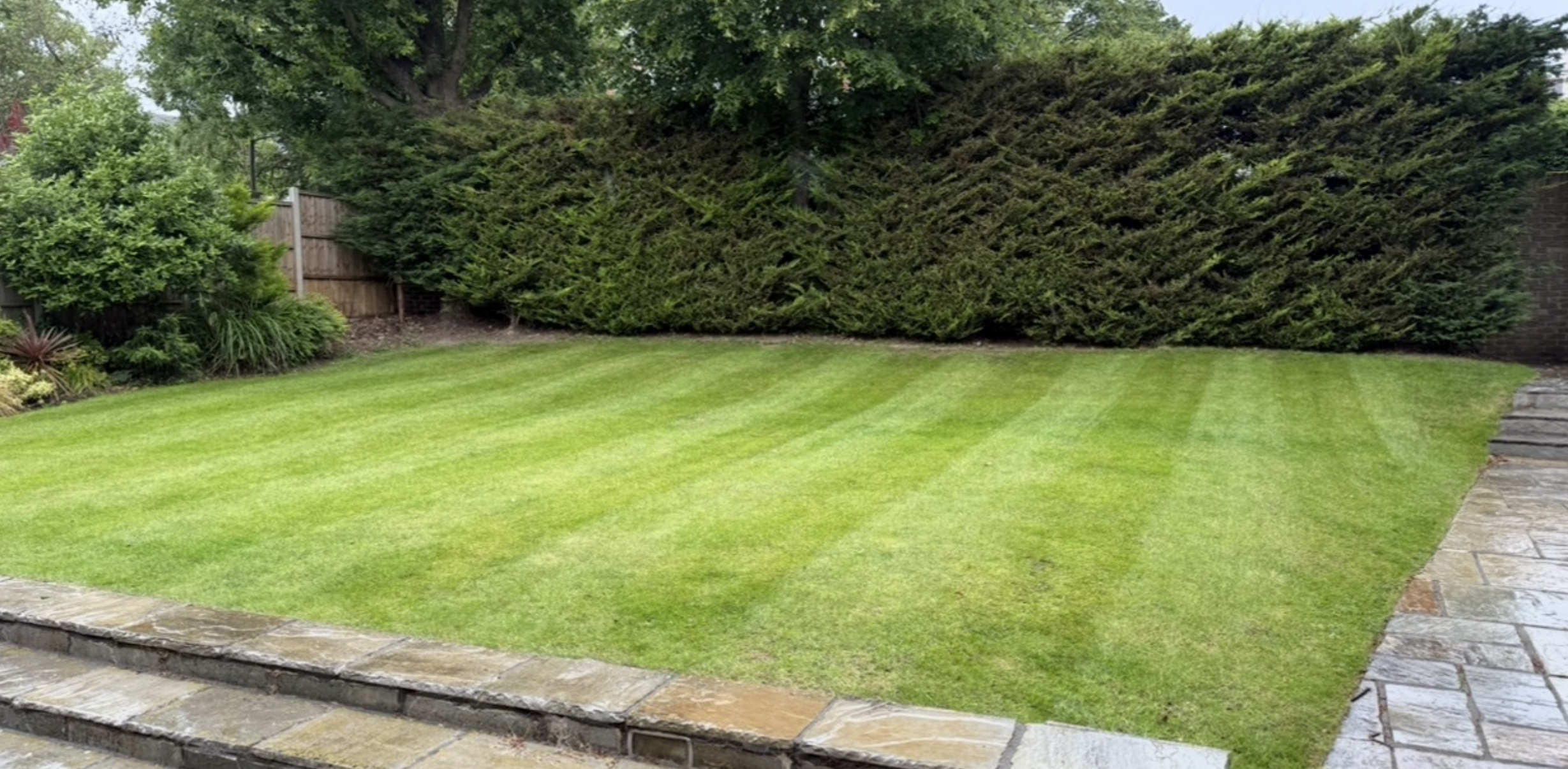 Freshly striped and edged lawn outside a brick house